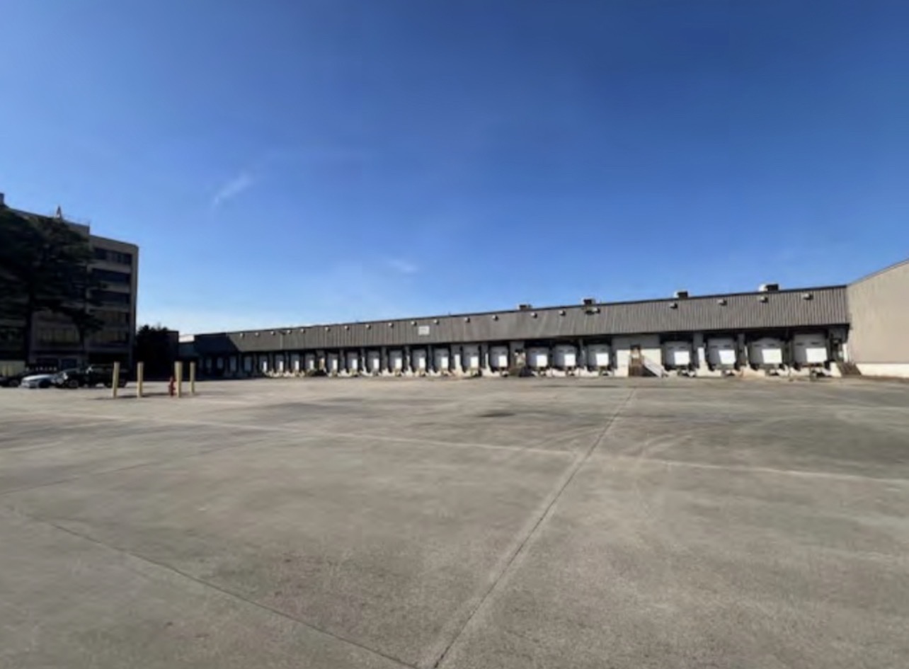 Long line of loading docks across a wide concrete yard on the campus
