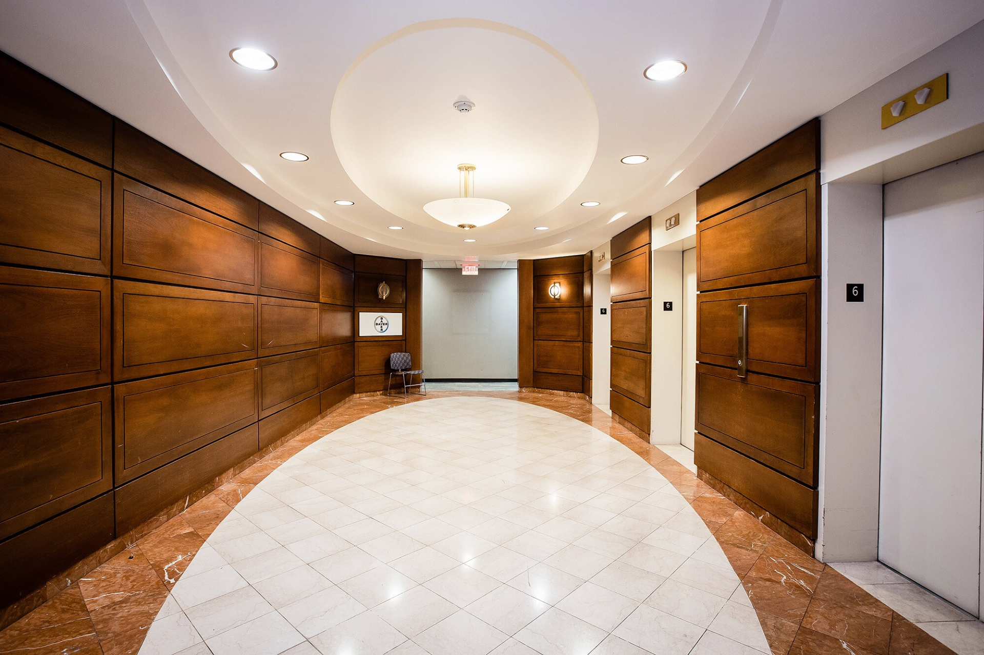 Polished marble and wood paneled lobby corridor with circular ceiling detail inside the campus tower